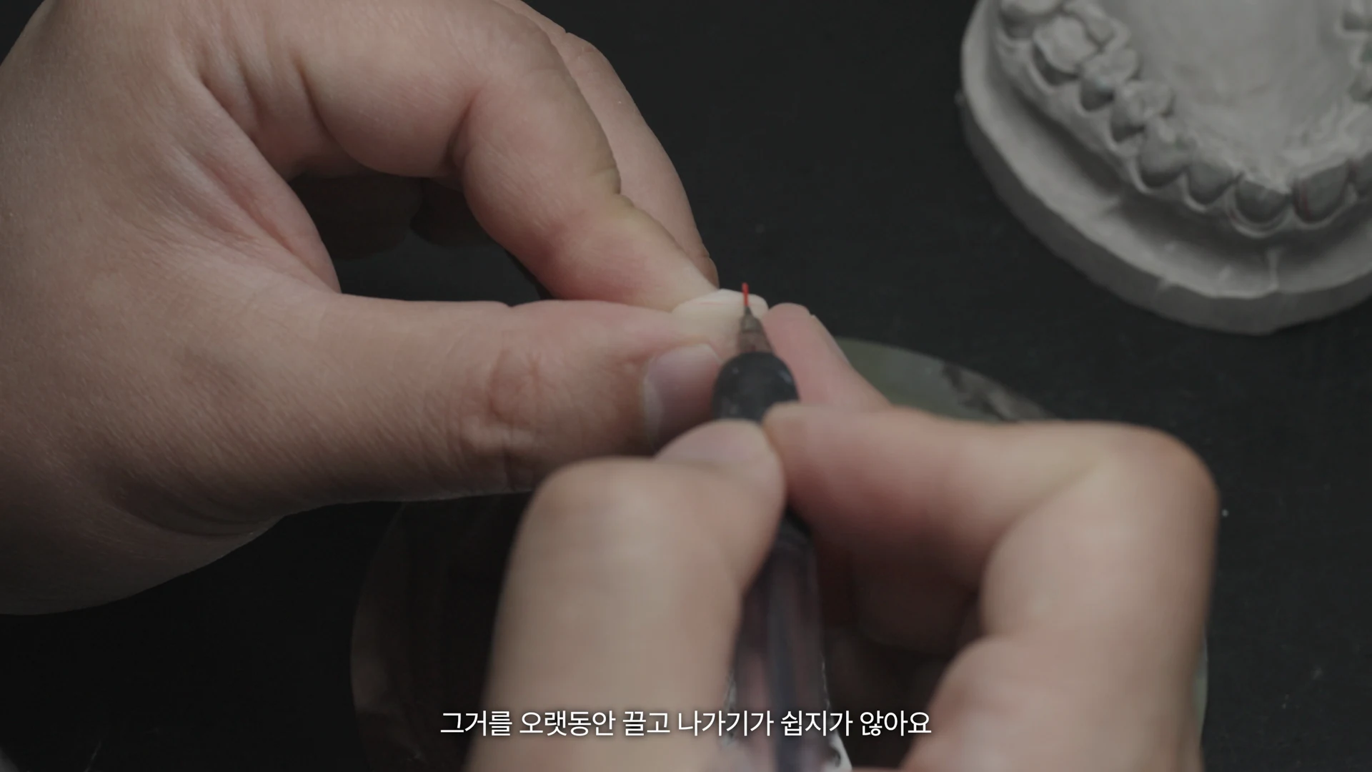 The laboratory lead’s hands holding a small piece and working on it with a tool